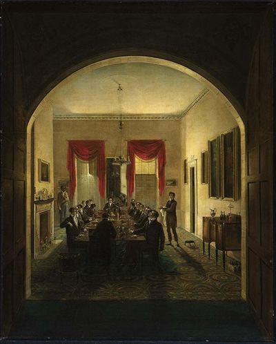 View of an early-19th-century scene of a dinner party with upper class men seated around a table with two servants standing on either side