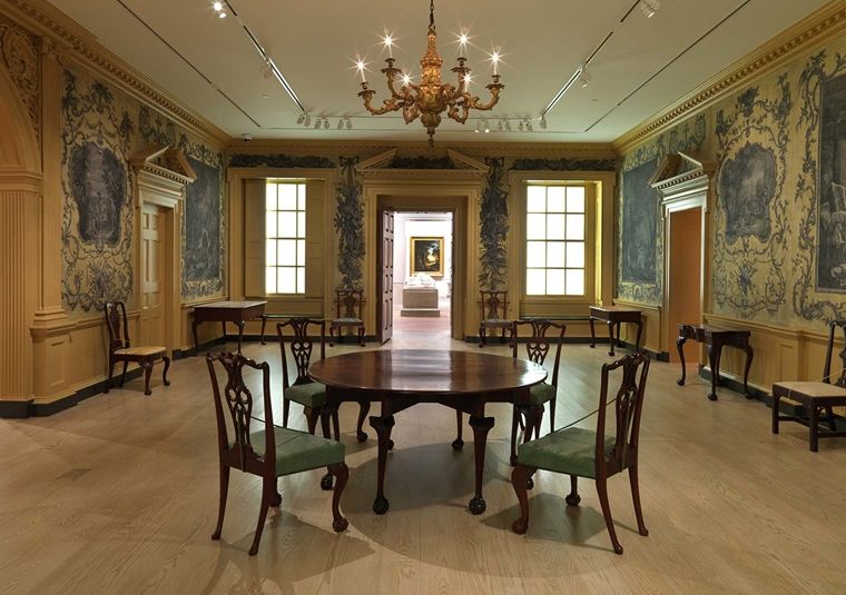 Photograph of the interior of a grand manor house, with yellow walls and painted floral details.