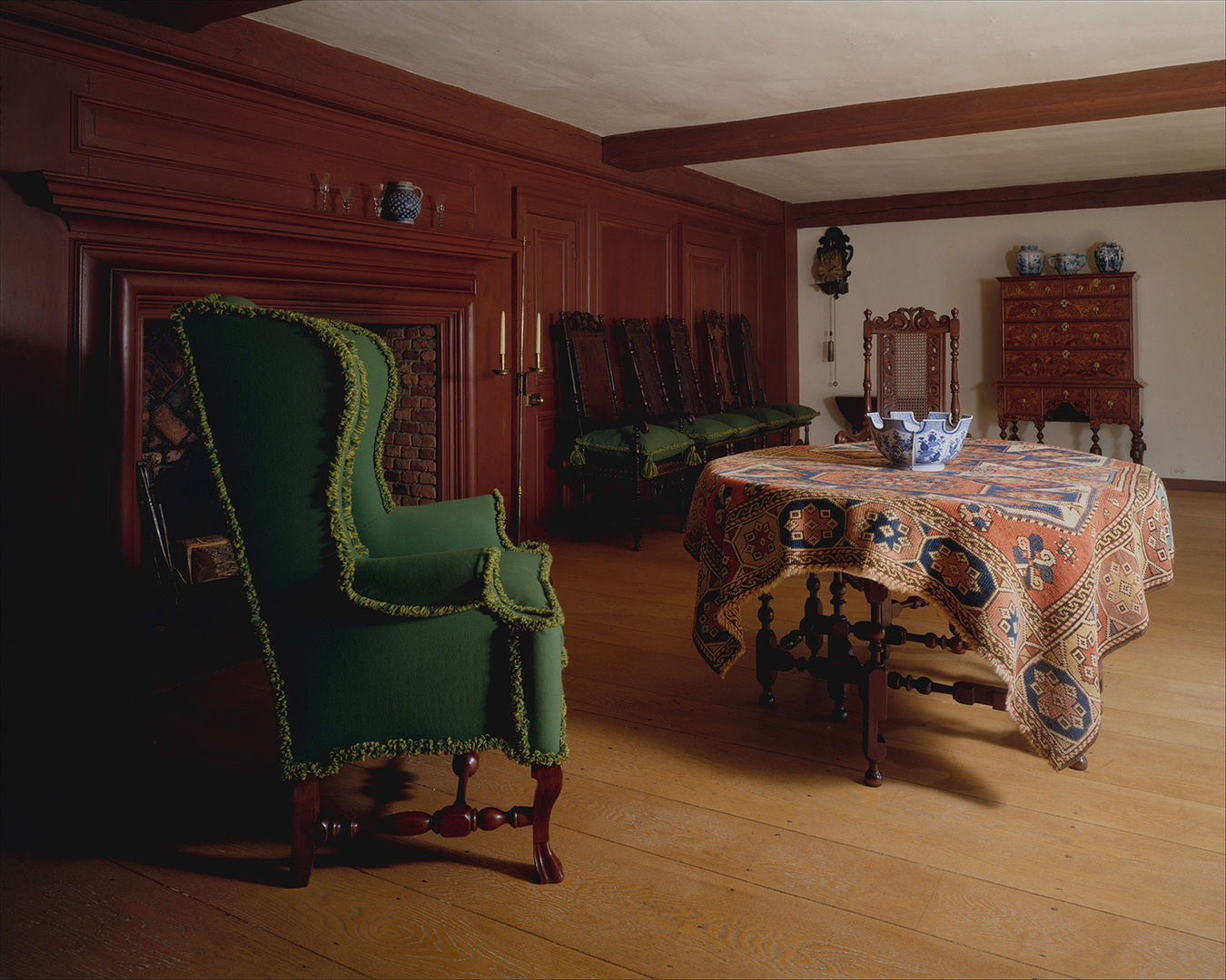 A green easy chair and a dining table draped with fabric installed in the Wentworth Room at The Met