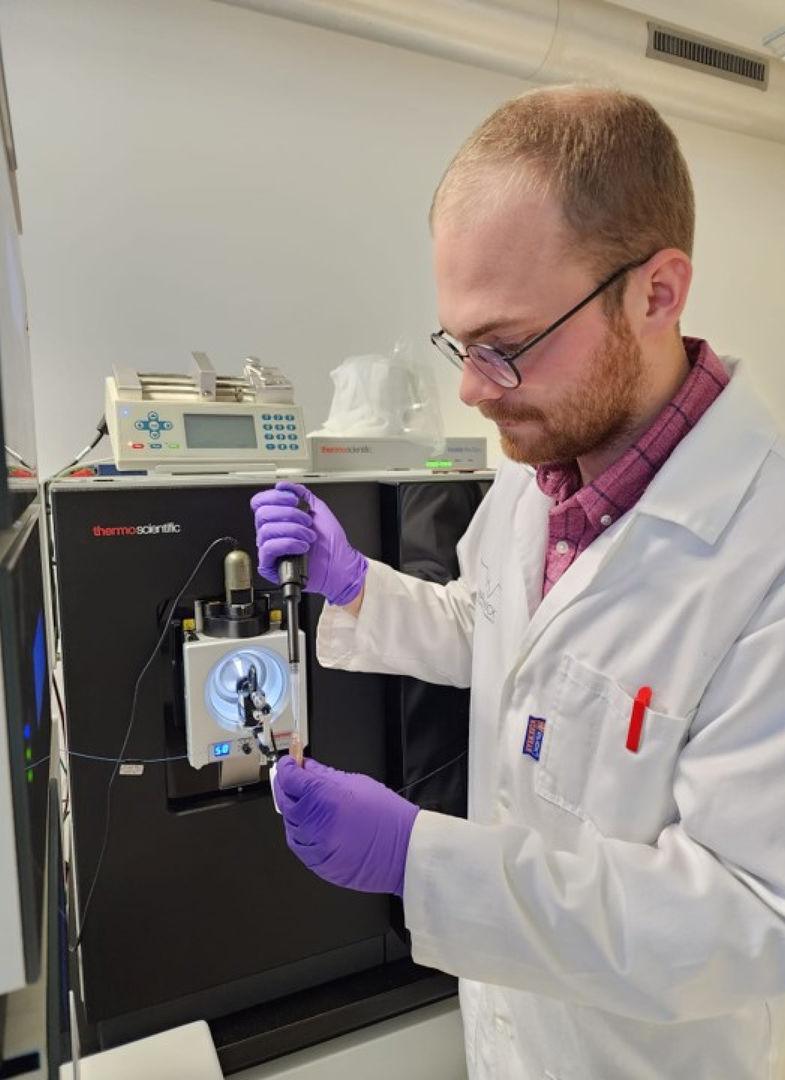 The scientist Vaclav Krupicka of the University of Bordeaux prepares a sample for injection onto a scientific instrument called the ThermoFisher Orbitrap Eclipse Tribrid Mass Spectrometer pictured in the background.