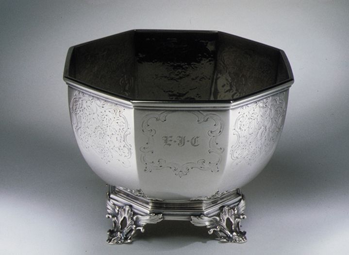 Small silver bowl with an inscription of initials in the center, and decorative etchings around the sides of the bowl.