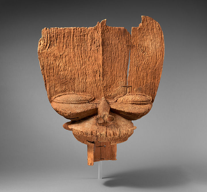 A wood crest from Cameroon with a long forehead and compressed facial features.