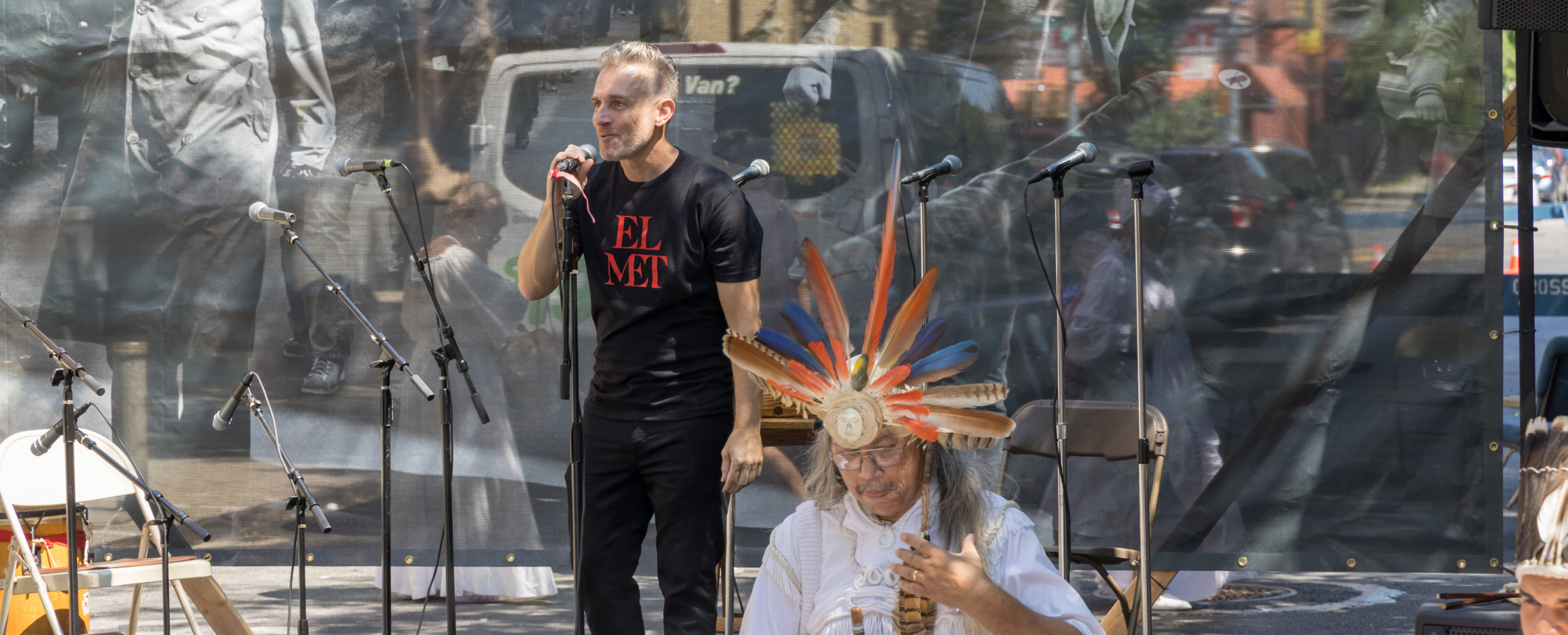 Miguel Luciano speaks into a microphone addressing attendees of a block party celebration.