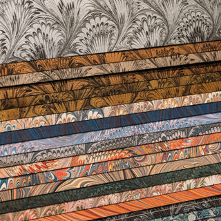 Photograph of a stack of marbled papers, spread to show a narrow band of each edge