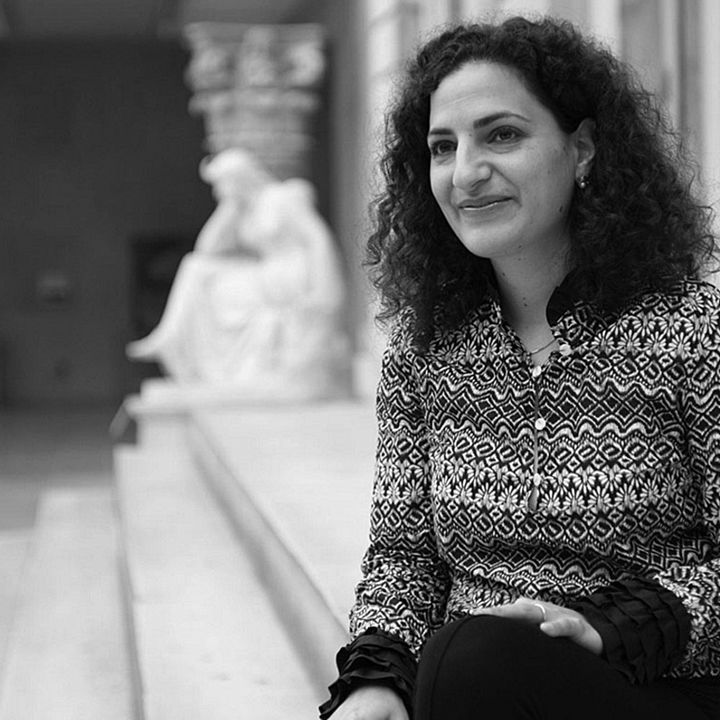 An elegant woman wearing a zigzag-striped jacket standing in a paintings gallery