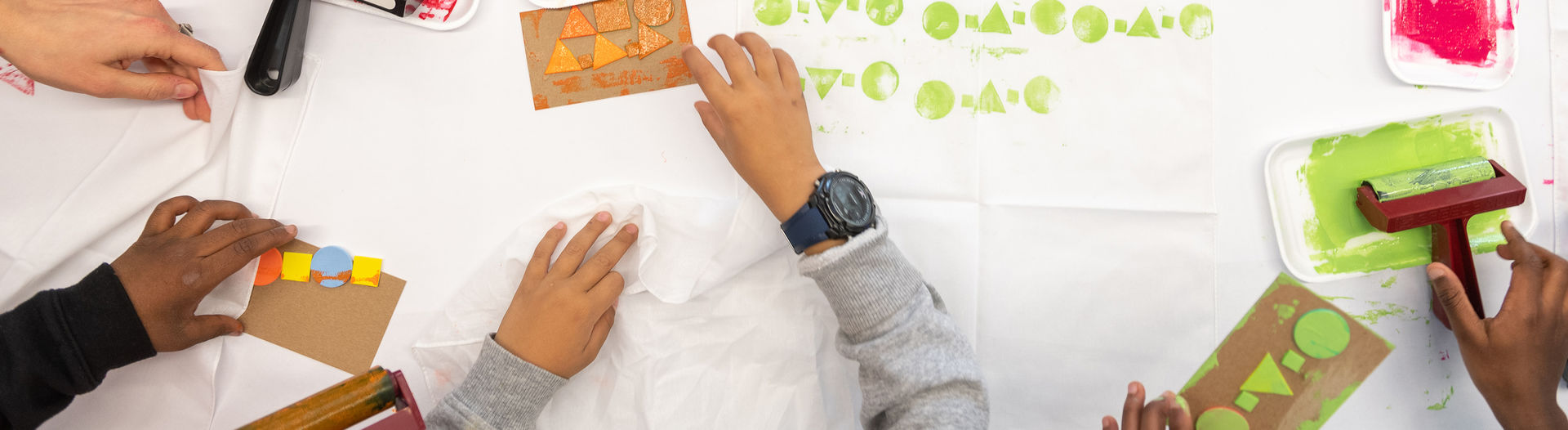 Children's hands making colorful block prints as seen from above.