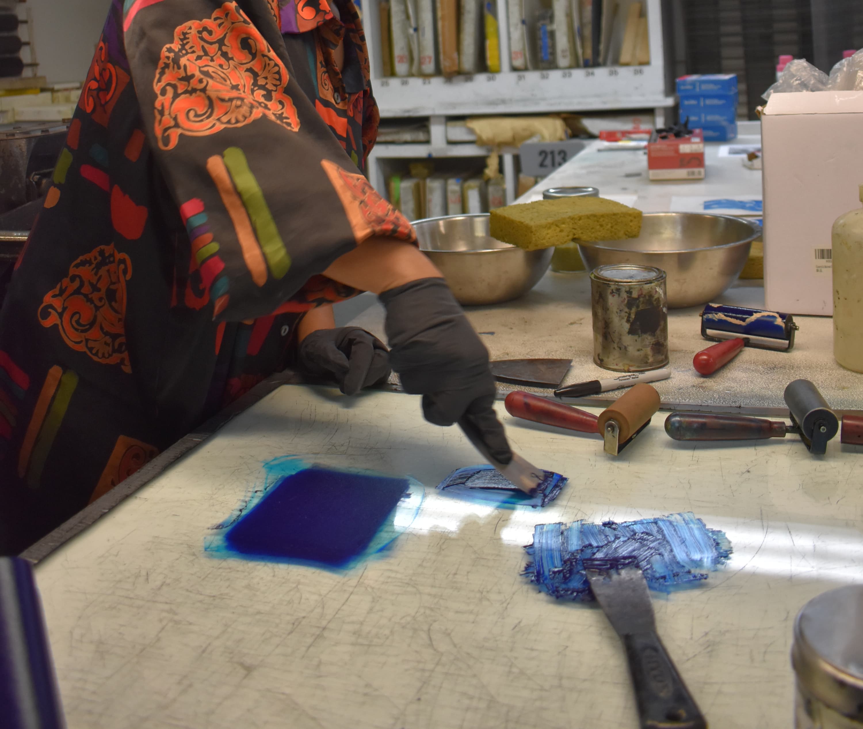Hands of printmaker rolling printing ink with a brayer.